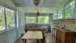 Un espace repas comprenant une table, des chaises et un mur en pierre.