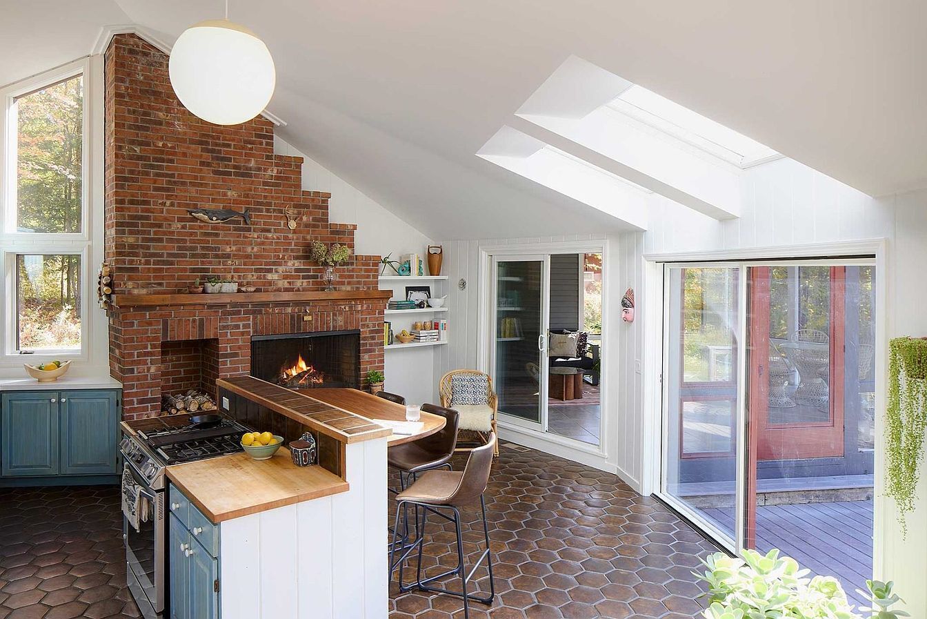 A kitchen with a brick wall, a stove, and a dining area with chairs.