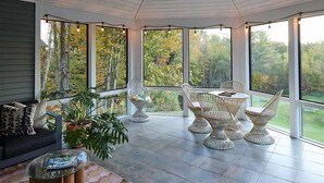 A sunroom with large windows, a sofa, chairs, and a coffee table. - Serene 4-bedroom family friendly house perfect for your Stowe getaway (Stowe)