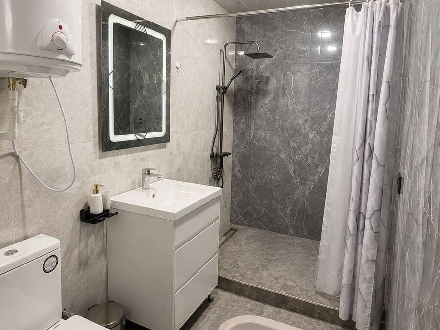 A modern bathroom with a toilet, sink, shower, and a mirror.