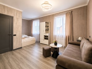 Una habitación de hotel moderna con cama, sofá, una mesita y un armario.
