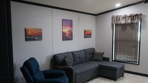 Una sala de estar moderna con un sofá modular, un sillón azul y tres cuadros colgados en la pared.