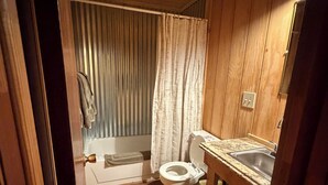 Ein Badezimmer aus Holz mit Toilette, Waschbecken und Duschvorhang.