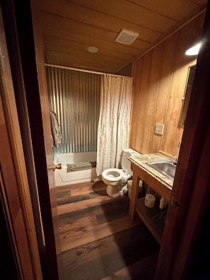 Puisesta materiaalista tehty kylpyhuone, jossa on wc, pesuallas ja suihkuverho.