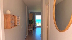 En hall med trägolv, en spegel på höger sida och utsikt över omgivningen.