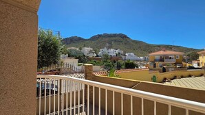 Zona residencial con casas, una montaña al fondo y un balcón con barandilla.