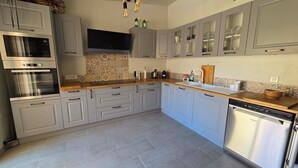 Una cocina moderna con gabinetes grises, electrodomésticos de acero inoxidable y un salpicadero de azulejos.
