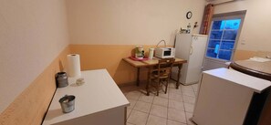 Une cuisine compacte équipée d’un réfrigérateur, d’un four à micro-ondes et d’une table en bois.