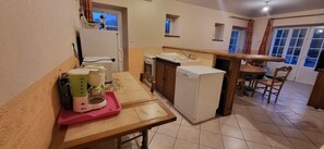 Une cuisine compacte comprenant un coin repas, un réfrigérateur, une machine à café et une fenêtre.