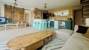 Een moderne woonkamer met een bank, een houten salontafel en een keuken met een barstoel.