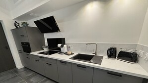 Eine moderne Küche mit doppelter Spüle, integriertem Backofen und einer Kaffeemaschine.