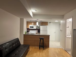 Eine moderne Küche mit einer zentralen Kochinsel, Holzschränken, einem schwarzen Ledersofa und Holzboden.