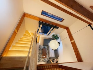 Eine Treppe führt zu einem Wohnbereich mit Deckenventilator, einem Fenster und einer Pflanze.