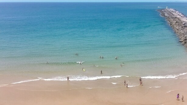 Een strand met mensen die zwemmen en over het strand lopen.