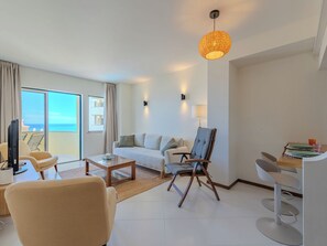 A modern living room with a sofa, armchairs, a coffee table, a TV, and a dining area with a table and chairs. - Algarvemor - Casa Do Tio by Interhome (Portimão)