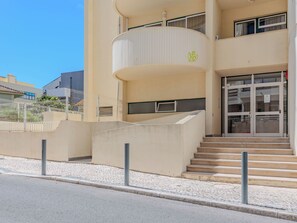 A building with a curved balcony, a set of stairs leading to the entrance, and a tiled pavement. - Algarvemor - Casa Do Tio by Interhome (Portimão)