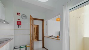 Een gang met een houten deur, een klok en een brandblusser aan de muur.