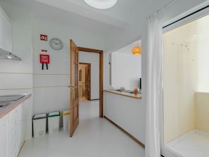 A hallway with a wooden door, a clock, and a fire extinguisher on the wall. - Algarvemor - Casa Do Tio by Interhome (Portimão)