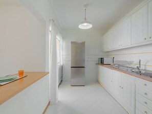 Une cuisine moderne avec des meubles blancs, un réfrigérateur en acier inoxydable, un four à micro-ondes et un plan de travail en bois.