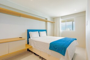 Ein modernes Schlafzimmer mit Bett, einer Bank, einem Fenster und Blick auf die Stadt.