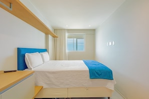 Ein Schlafzimmer mit einem Bett, einem Nachttisch, einem Fenster und einer Deckenleuchte.
