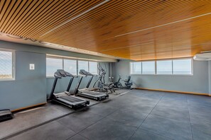 Academia com esteiras, bicicletas ergométricas e máquina de remo.