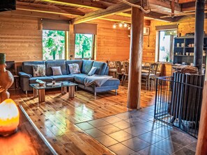 A wooden interior with a sofa, coffee table, and dining area. - Chata Ujo by Interhome (Hranice)