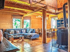 A wooden interior with a sofa, dining table, chairs, and a fireplace. - Chata Ujo by Interhome (Hranice)