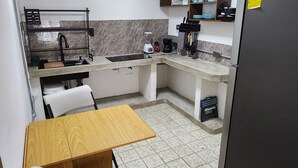 A compact kitchen with a dining table, chairs, a refrigerator, and a built-in oven. - Newly Remodeled Loft - Fast WiFi - A/C - 9 Min drive to Malecon (La Paz)