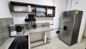 A kitchen with a built-in stove, a refrigerator, a coffee maker, and a shelf with dishes. - Newly Remodeled Loft - Fast WiFi - A/C - 9 Min drive to Malecon (La Paz)