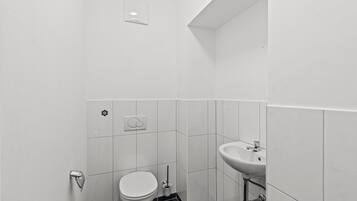 A small, modern bathroom with a toilet, sink, and a wall-mounted light fixture.