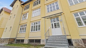 A multi-story yellow building with white-framed windows, a metal staircase, and a door marked with the number 18. - Faraway Homes Studios Krieglach 18 (Sommer)