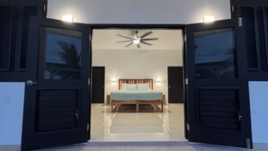 Een slaapkamer met een bed, een plafondventilator en een nachtkastje.
