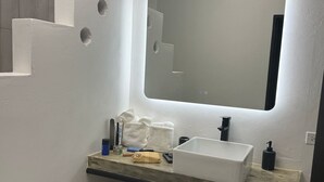 Een badkamer met een witte wasbak, spiegel en handdoekrek.