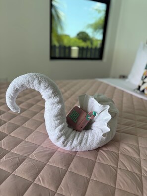 A swan-shaped pillow with a speaker on a bed.