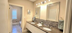 A bathroom with two sinks, a large mirror, and a shower.