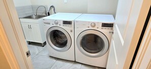 A laundry area with two front-loading washing machines, a sink, and a cabinet.