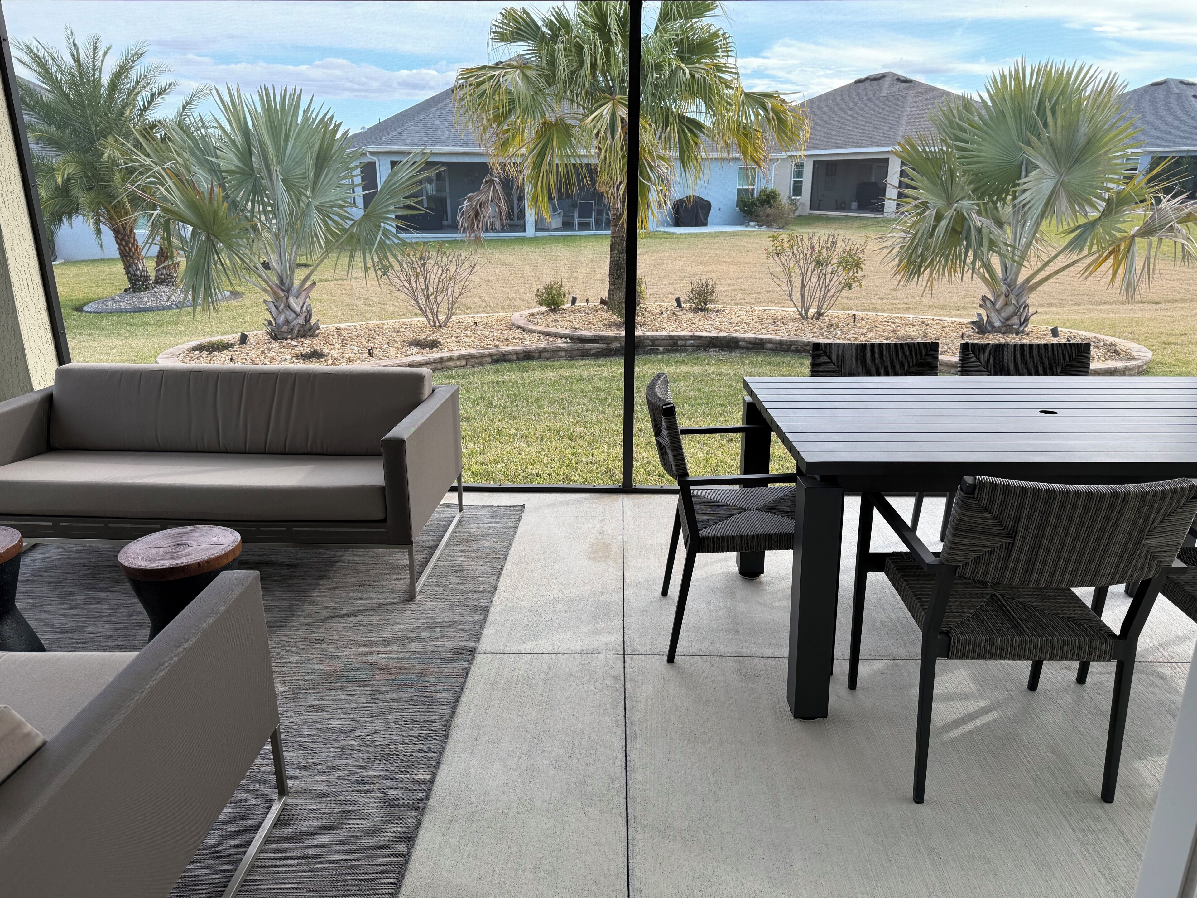 Un espace patio aménagé avec un canapé, une table à manger, des chaises et une vue sur un quartier résidentiel.