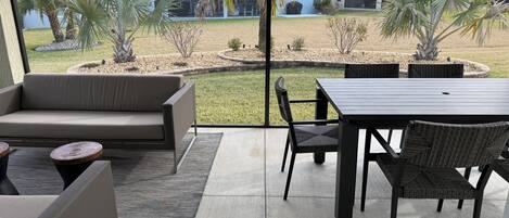 Un espace patio aménagé avec un canapé, une table à manger, des chaises et une vue sur un quartier résidentiel.