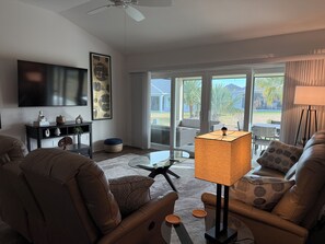 Una sala de estar con sofá, mesa de centro, televisor y lámpara.