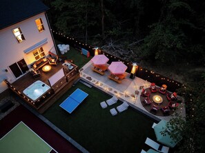 Ein Garten mit Whirlpool, Sitzgelegenheit im Freien, einem Tischtennis-Tisch und einer Feuerstelle.