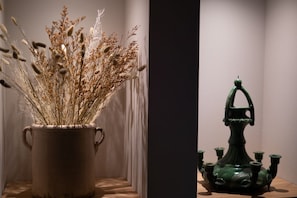 A vase with dried plants and a green ceramic sculpture.