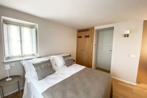 Ein Schlafzimmer mit Bett, Fenster, Tür und einem kleinen Tisch.