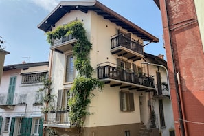 A multi-story building with balconies, a visible staircase, and a brick wall.