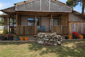 Une maison en bois avec un porche couvert, un mur en pierre et des plantes en pot.