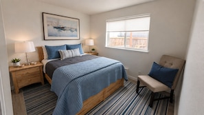 Une chambre à coucher avec un lit, des tables de chevet, une chaise, une fenêtre et un tableau au mur.