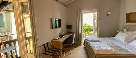 A bedroom with a bed, a desk, a chair, a TV, and a balcony.