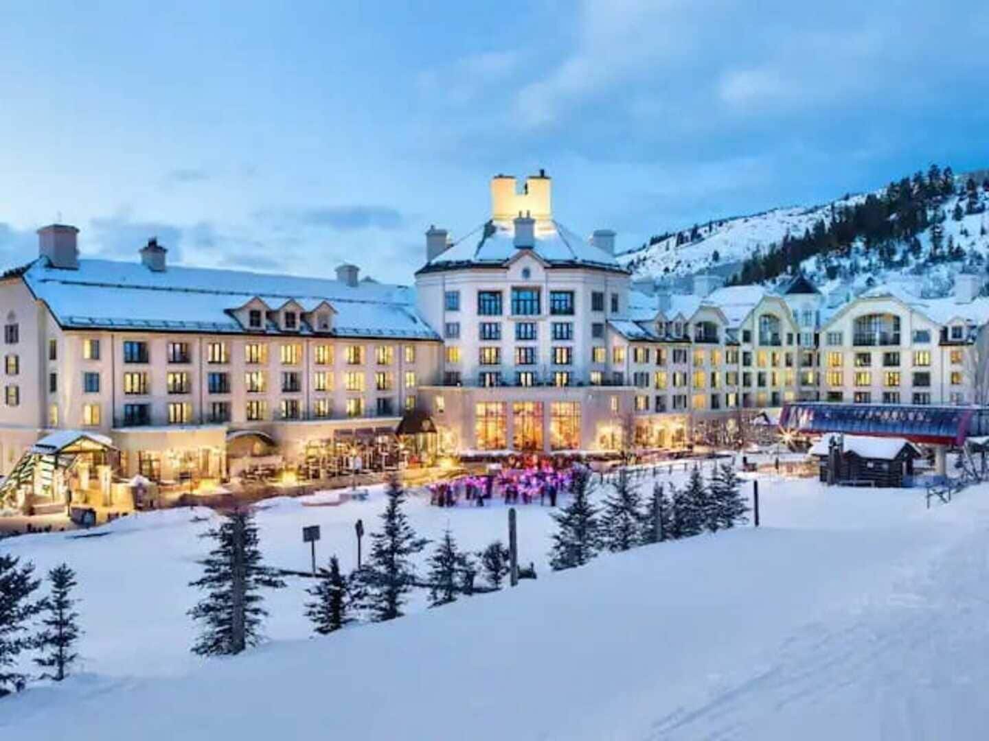 A large hotel with multiple buildings, a ski slope, and snow-covered trees.