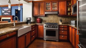 Una cocina con gabinetes de madera, estufa de acero inoxidable, microondas y encimeras de granito.