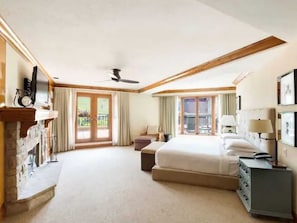 A hotel room with a large bed, a desk, a chair, a dresser, a ceiling fan, and a view of the outdoors through the windows. - 2-bedroom residence in luxury resort with spa & nightly turn down service (Avon)
